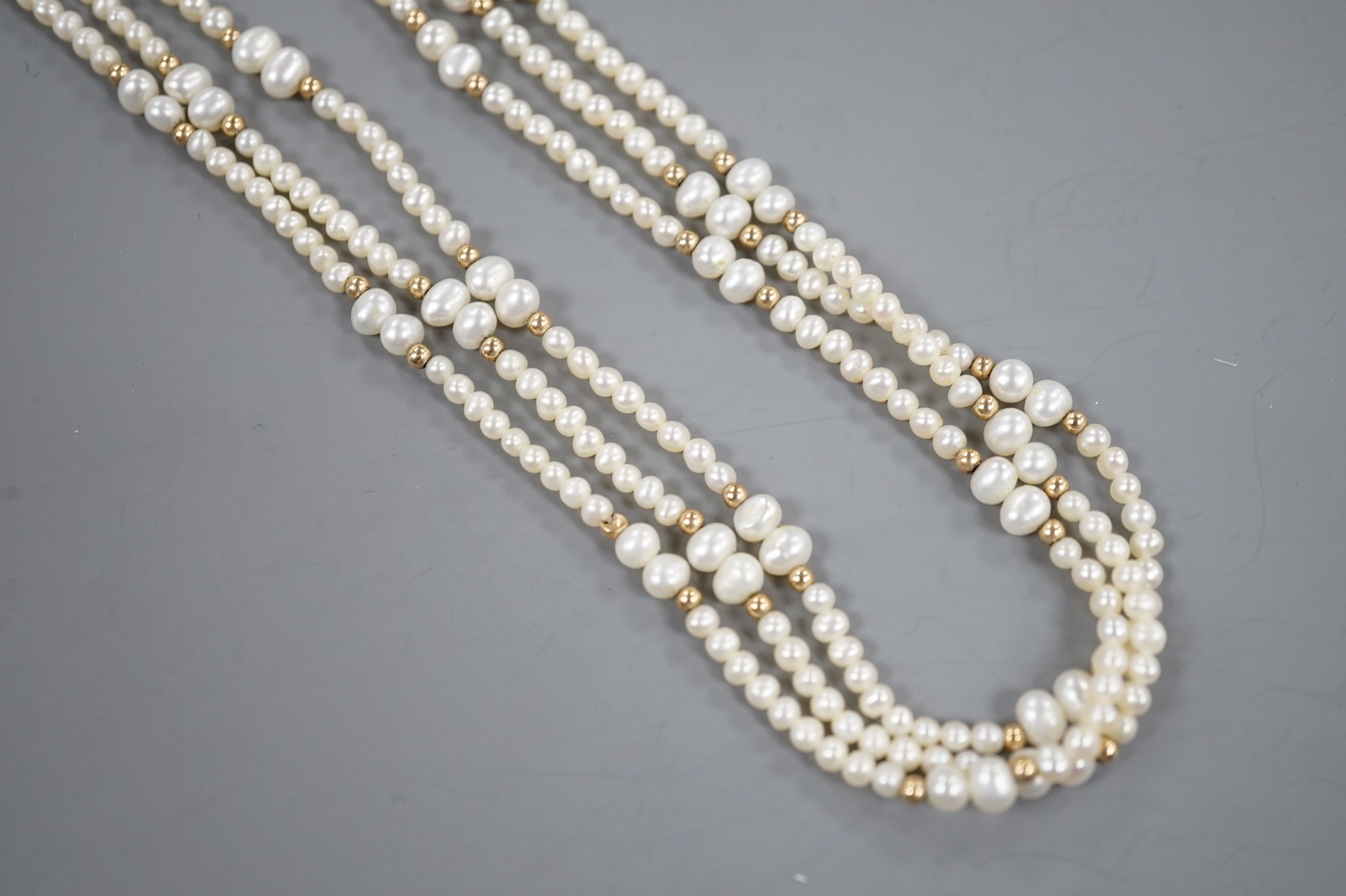 A modern 9k mounted triple strand cultured pearl necklace, 39cm, with yellow metal spacers.